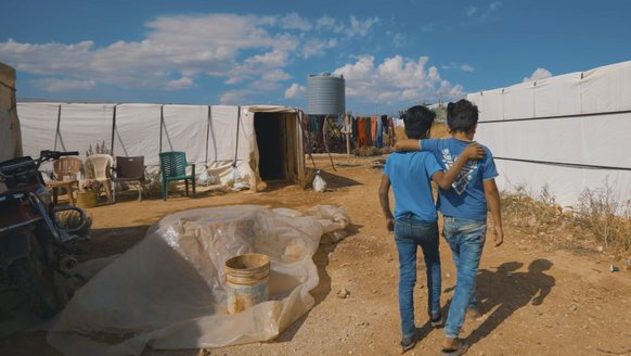 Syrian friends walking through refugee settlement in Lebanon
