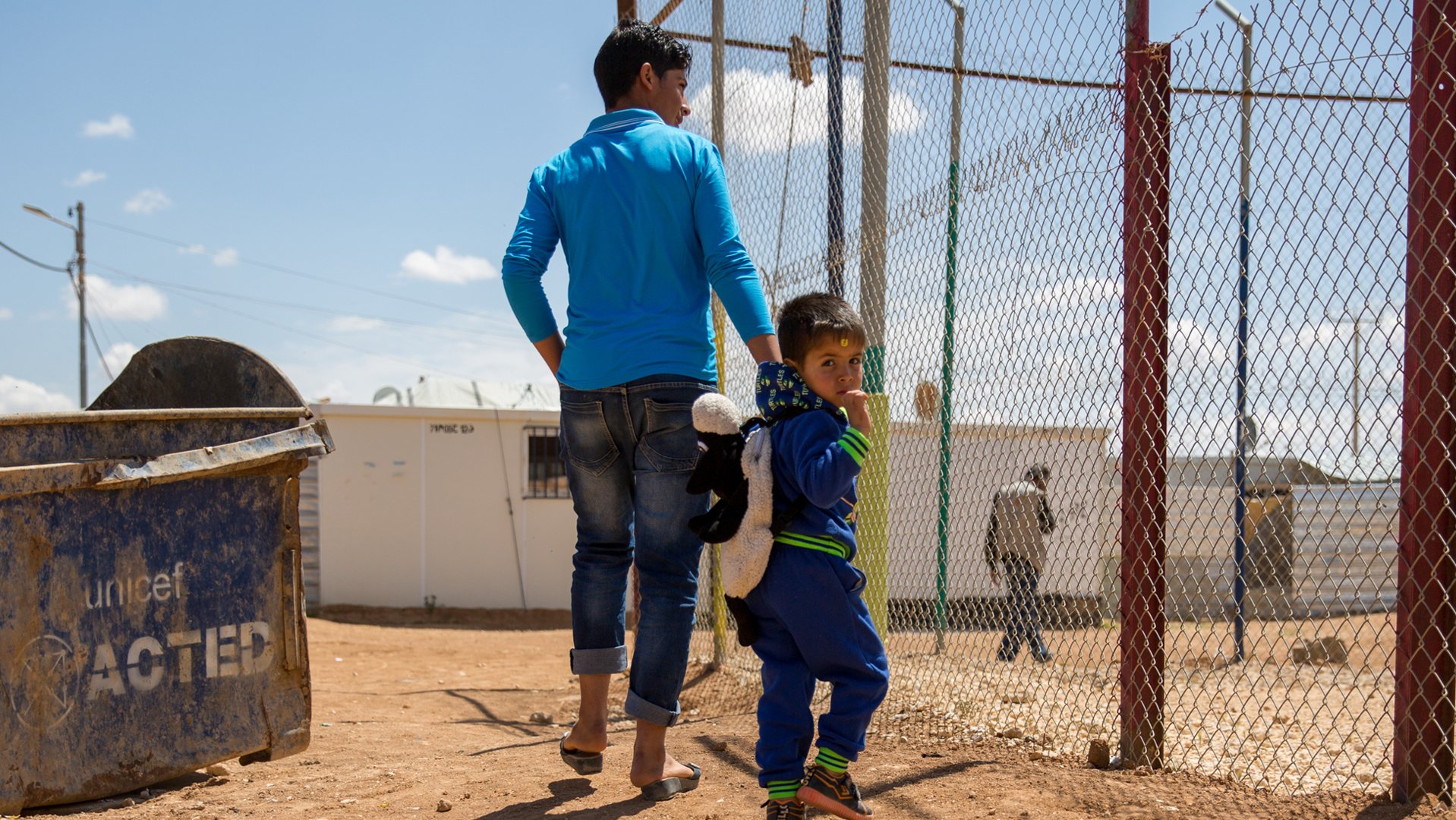 Teenager with little boy walking in refugee camp - War Child - Caregiver Support Intervention