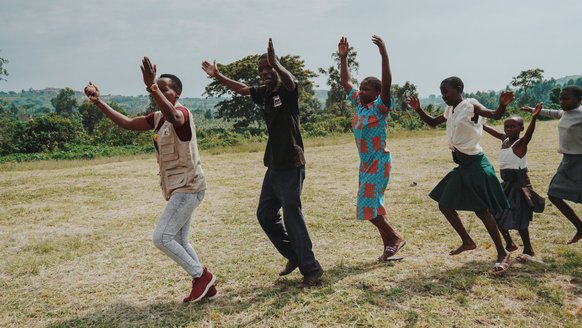 Kind en begeleiders in Oeganda dansend met TeamUp War Child