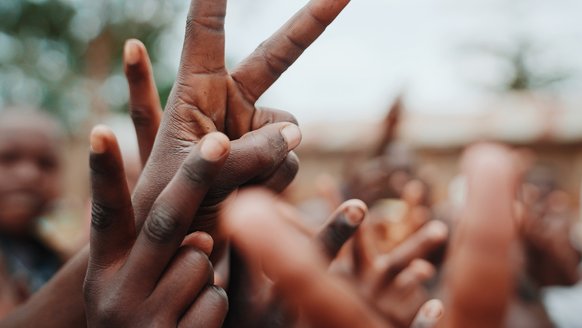 Children in Uganda make peace sign with their hands - War Child