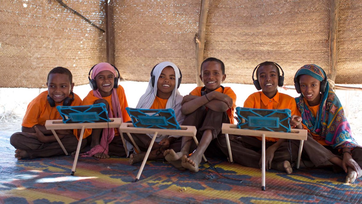 Six children, smiling with headphones and tablets with Can't Wait to Learn, War Child's  learning app