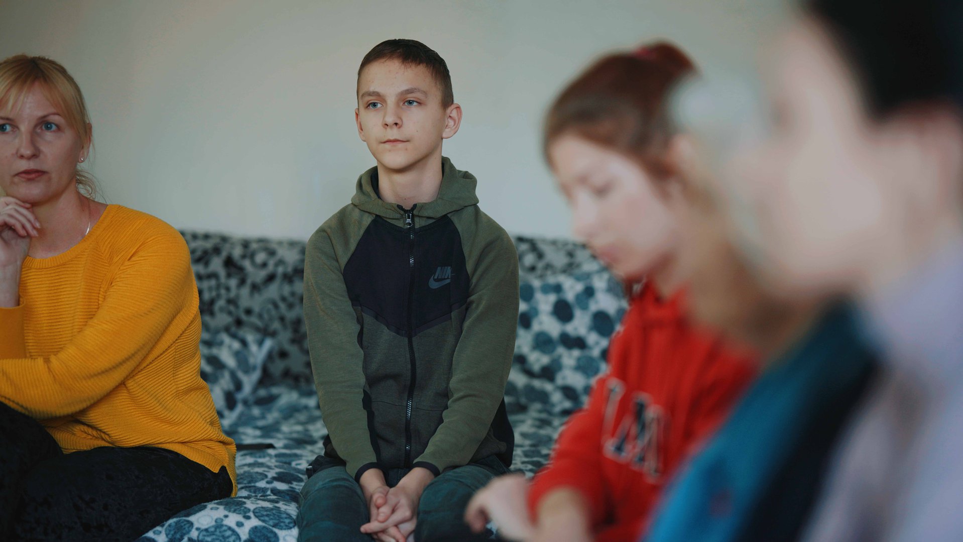 Ihor, a teenage boy from Ukraine, sitting with his family in a living room in Moldava