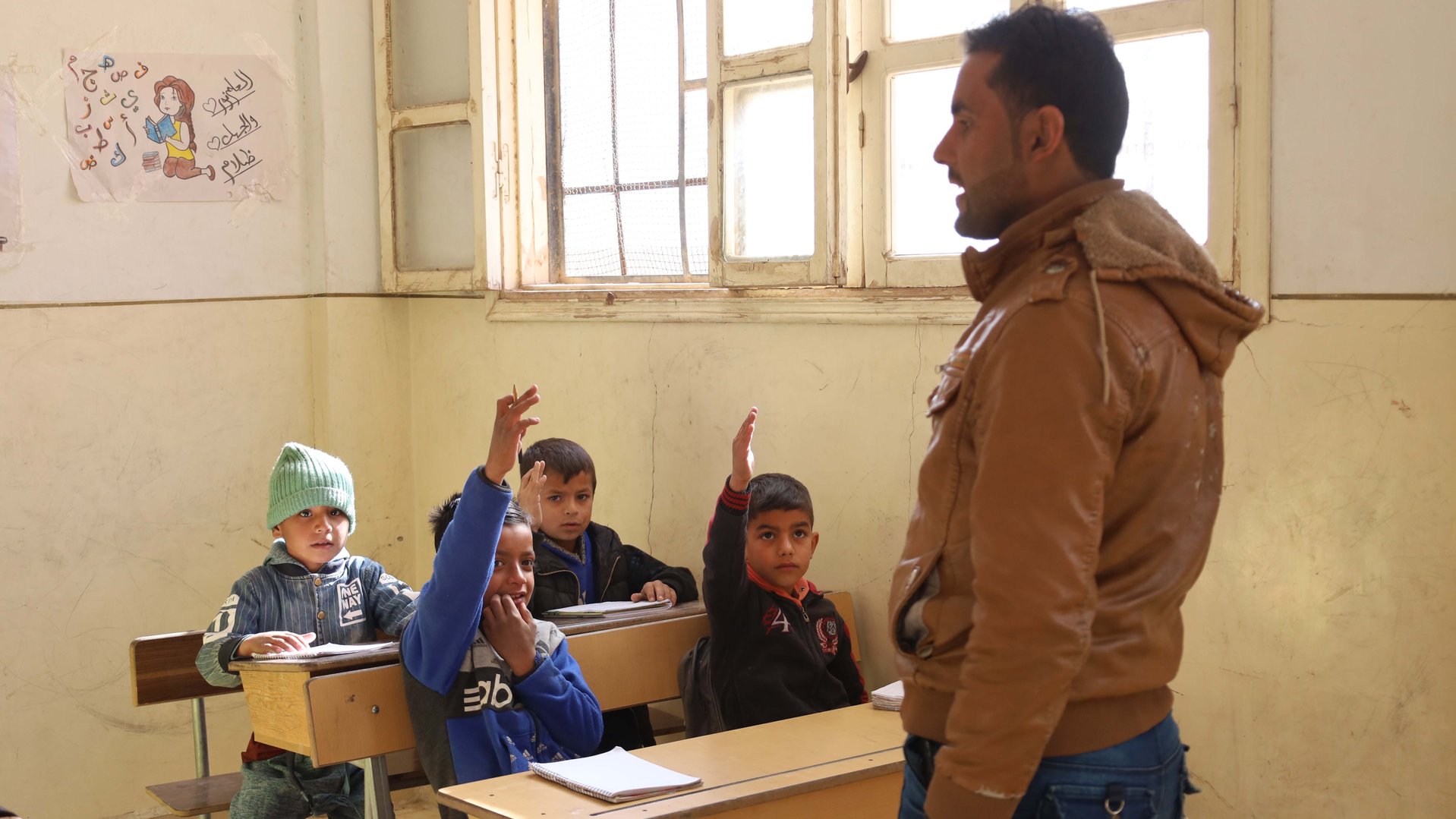 Muhammad, 9 years old, at school raising his hand in the class, part of War Child's Syria Response