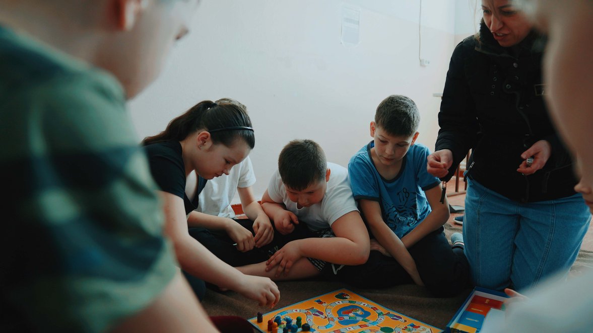 Ukranian children play a game with a Pyschological First Aid Worker in a shelter in Moldova.